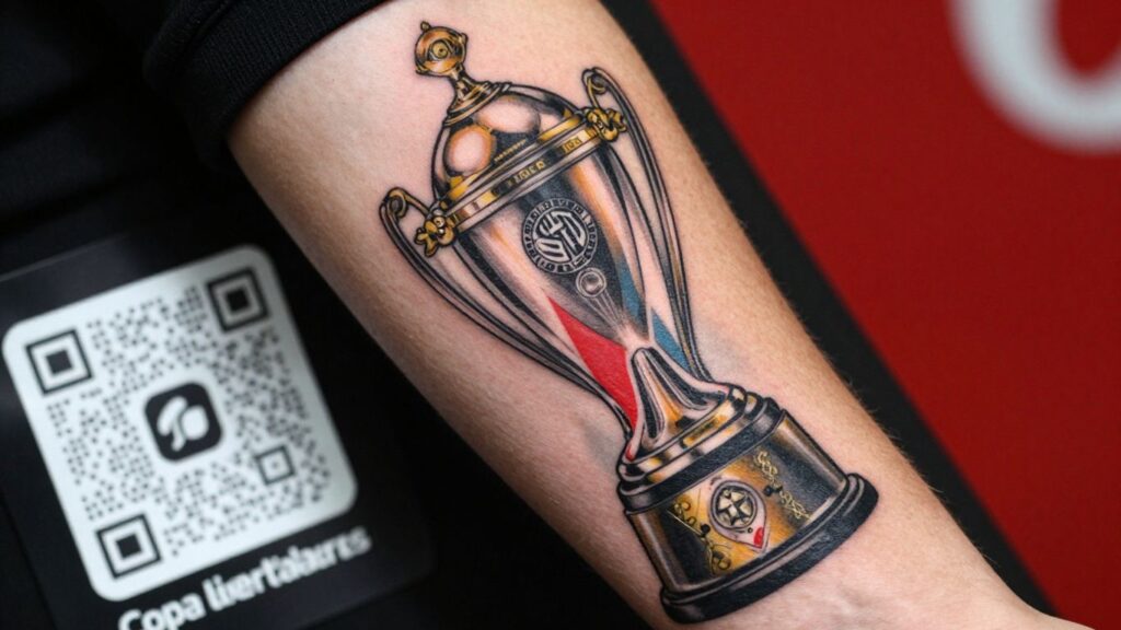 Fan's arm tattoo of Copa Libertadores trophy with QR code.